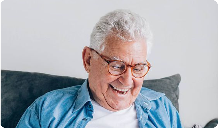 Smiling Older Man on Gray Couch